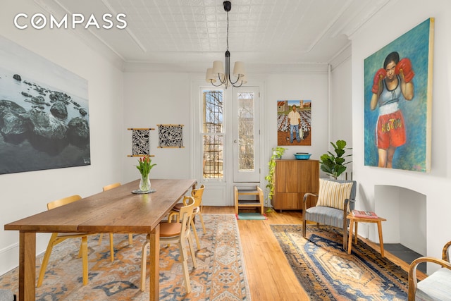 dining room featuring light wood finished floors, a notable chandelier, and ornamental molding