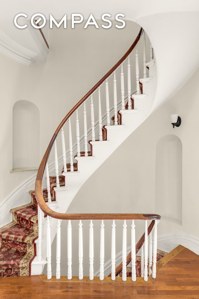 staircase with crown molding and wood finished floors