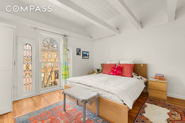 bedroom with lofted ceiling with beams, access to outside, and wood finished floors