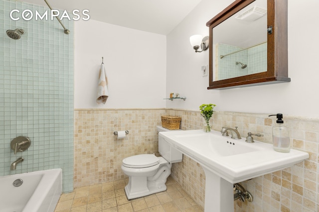 full bath with visible vents, toilet, wainscoting, tile walls, and  shower combination