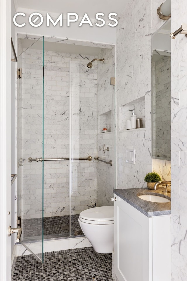 full bath with toilet, tile walls, a stall shower, and vanity