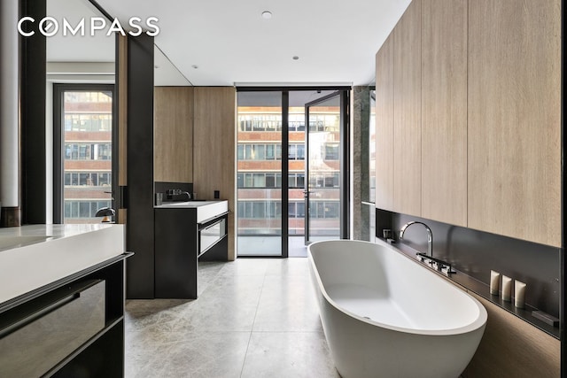 bathroom with expansive windows, a soaking tub, concrete floors, and vanity