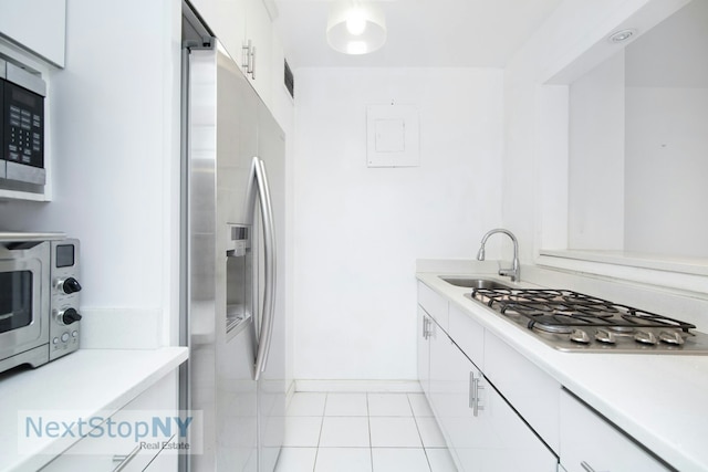 kitchen with light countertops, white cabinets, appliances with stainless steel finishes, and a sink