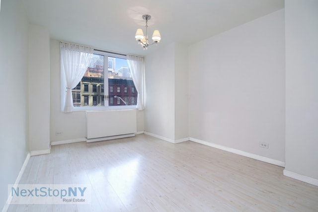 unfurnished room with wood finished floors, baseboards, and a chandelier