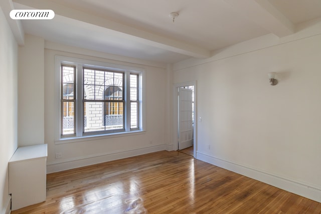 empty room with beamed ceiling, visible vents, and wood finished floors