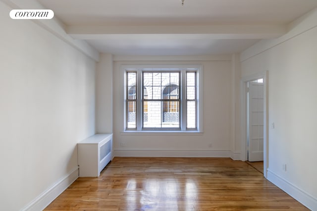 spare room with beamed ceiling, baseboards, visible vents, and light wood finished floors