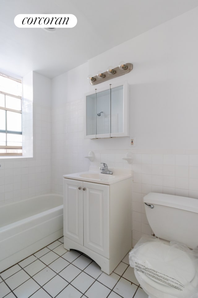 full bathroom featuring tile patterned flooring, a tub, toilet, vanity, and tile walls