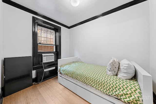 bedroom featuring cooling unit, crown molding, and light wood finished floors