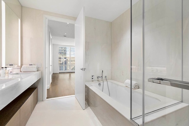 full bathroom with double vanity, a garden tub, and an enclosed shower