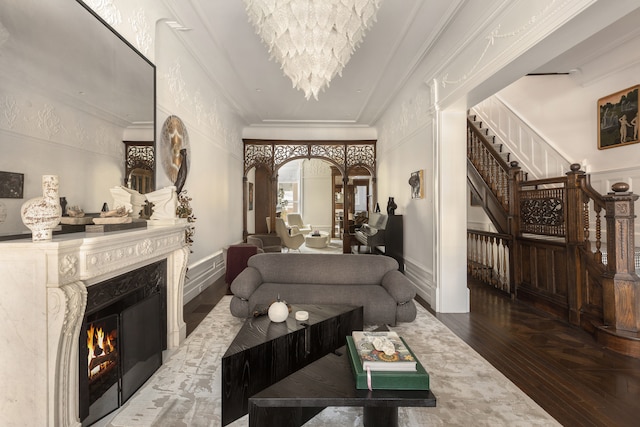 living room with a notable chandelier, wood finished floors, stairway, crown molding, and a premium fireplace