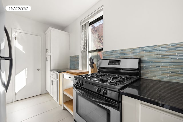 kitchen featuring dark countertops, visible vents, backsplash, stainless steel range with gas cooktop, and white cabinetry