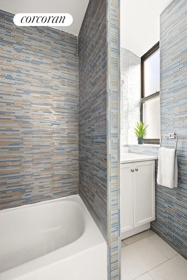 full bathroom with tile patterned flooring, vanity, a bathtub, and tile walls