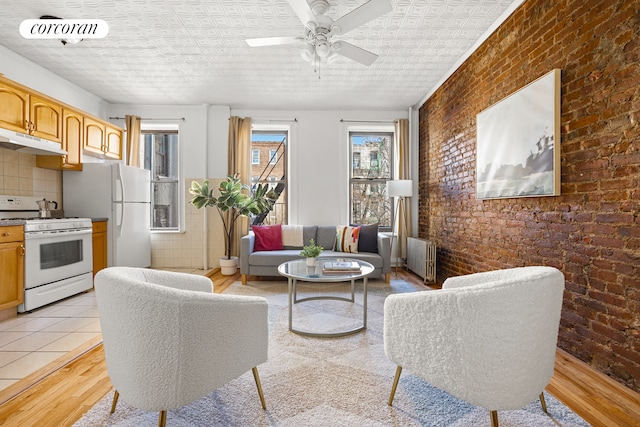 living room featuring visible vents, light wood-style flooring, brick wall, and radiator