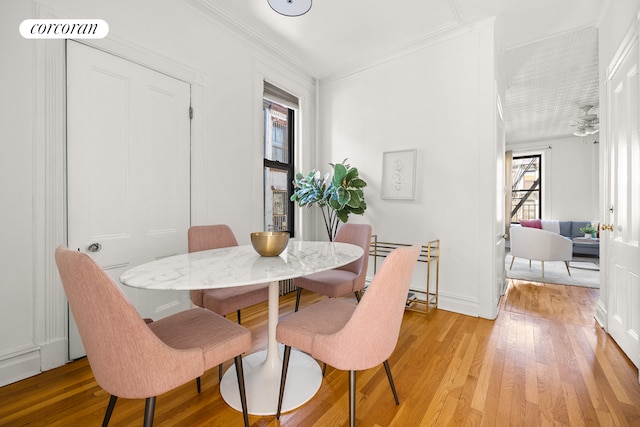 dining room featuring visible vents, baseboards, light wood-style flooring, and crown molding