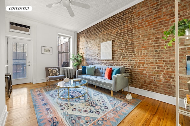 living room featuring baseboards, wood finished floors, visible vents, and brick wall