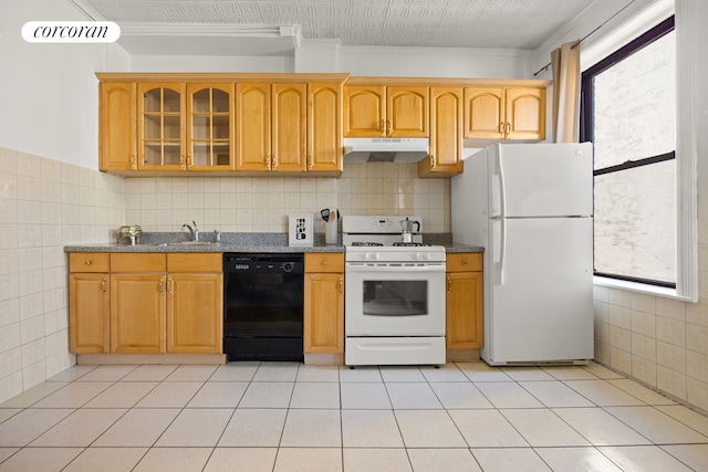 kitchen featuring white appliances, dark stone countertops, a sink, glass insert cabinets, and under cabinet range hood