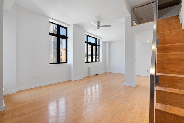 empty room with light wood-style flooring, radiator, baseboards, and ceiling fan