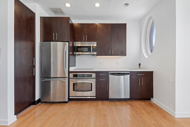 kitchen featuring visible vents, dark brown cabinetry, appliances with stainless steel finishes, and light wood-style flooring