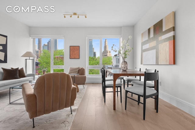 dining area featuring light wood finished floors, a view of city, and baseboards