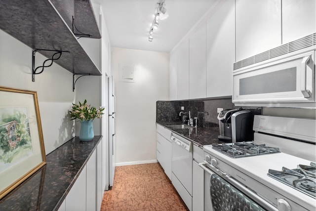 kitchen with a sink, dark stone countertops, tasteful backsplash, white appliances, and white cabinets