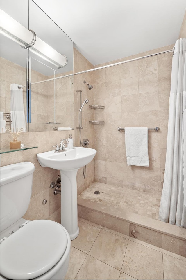 full bath featuring tile patterned floors, a tile shower, toilet, and tile walls