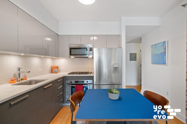 kitchen featuring a sink, gray cabinetry, appliances with stainless steel finishes, modern cabinets, and backsplash