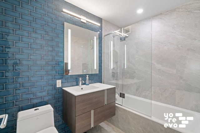 bathroom featuring vanity, toilet, tile walls, and shower / bathtub combination