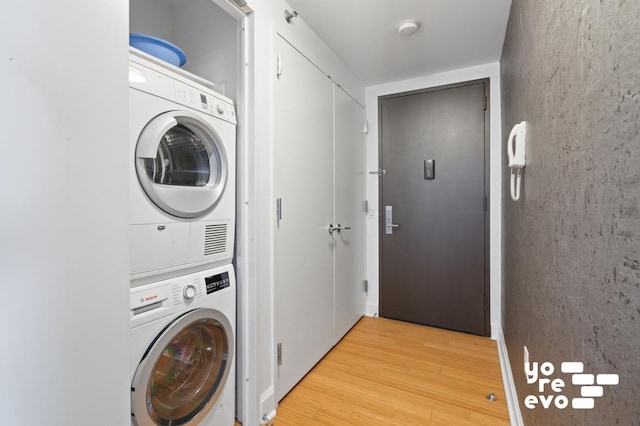 clothes washing area with light wood-style flooring and stacked washer / drying machine