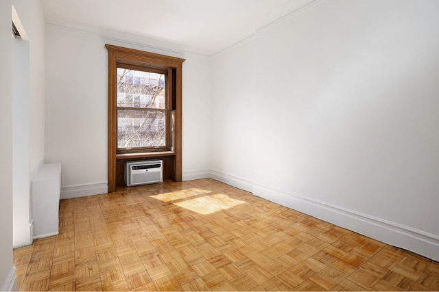 spare room featuring an AC wall unit, baseboards, and ornamental molding