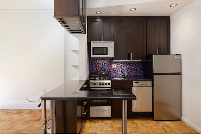 161 W 76th St Unit 3F, New York City, NY 10023 - kitchen featuring freestanding refrigerator, white microwave, dishwashing machine, dark brown cabinetry, and dark countertops