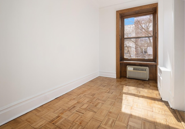 spare room featuring baseboards, an AC wall unit, and crown molding