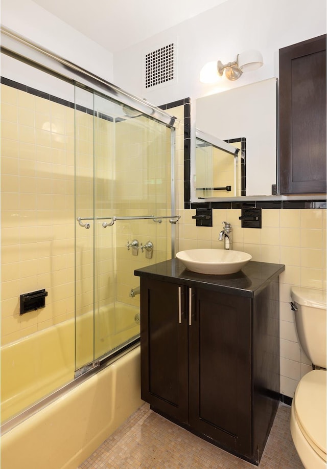 full bathroom with visible vents, toilet, tile patterned floors, tile walls, and enclosed tub / shower combo