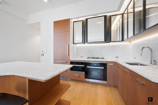 110 Charlton St Unit 20-G, New York City, NY 10014 - kitchen with black oven, a sink, oven, brown cabinets, and modern cabinets