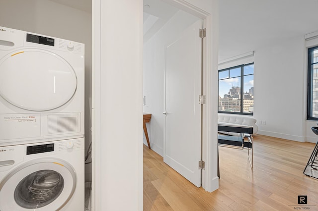 110 Charlton St Unit 20-G, New York City, NY 10014 - washroom featuring stacked washer / drying machine, light wood-style flooring, and baseboards