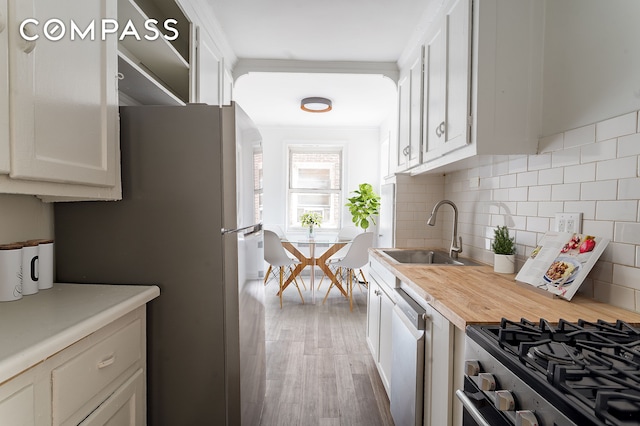 kitchen featuring wood counters, backsplash, appliances with stainless steel finishes, and a sink