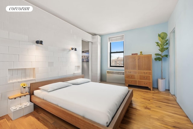 bedroom with radiator and light wood-style floors