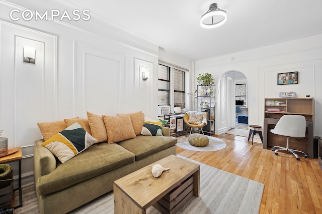 living room featuring arched walkways, light wood finished floors, and an office area