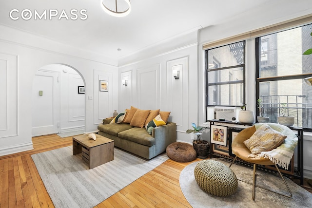 living room with arched walkways, a decorative wall, cooling unit, and hardwood / wood-style floors