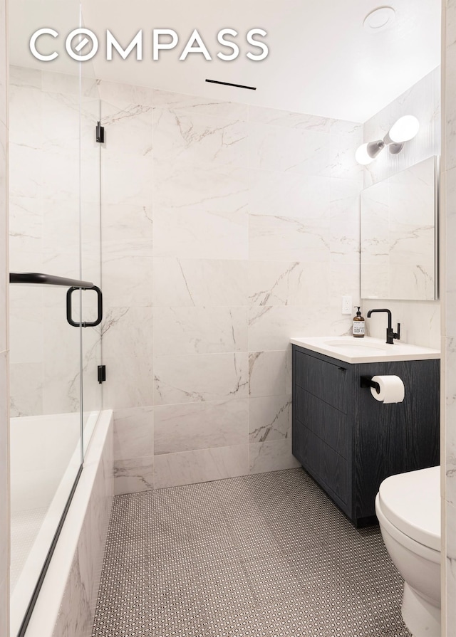 bathroom featuring toilet, tiled shower, and vanity