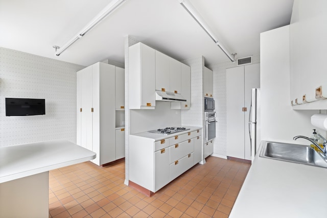 kitchen with visible vents, under cabinet range hood, gas stovetop, wall oven, and wallpapered walls