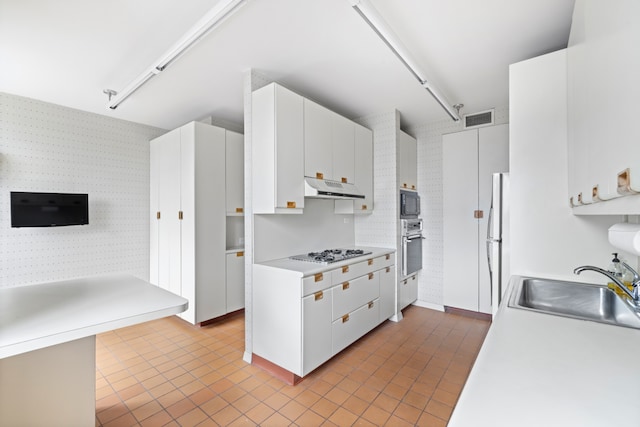 15 W 53rd St Unit 37Af, New York City, NY 10019 - kitchen featuring stainless steel appliances, wallpapered walls, under cabinet range hood, a sink, and track lighting