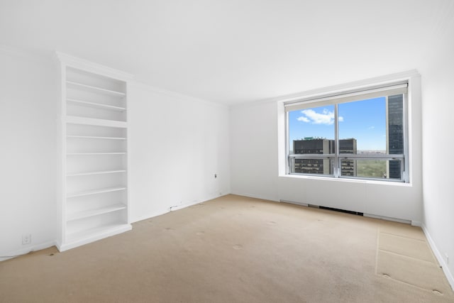 empty room with carpet flooring, crown molding, and baseboards