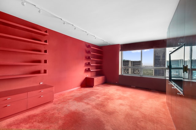 unfurnished living room with light colored carpet, a city view, and rail lighting