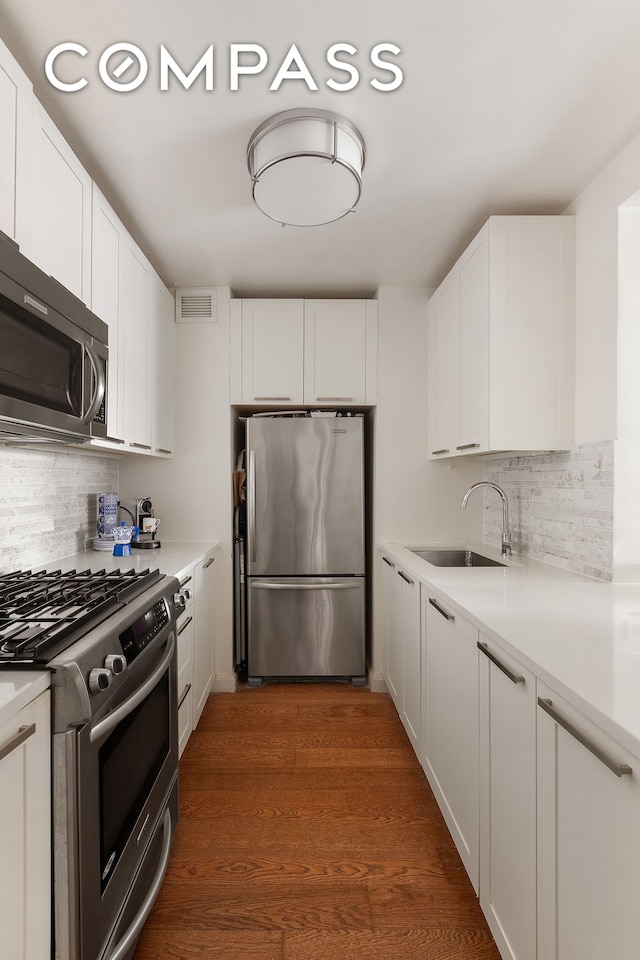 kitchen featuring a sink, light countertops, stainless steel appliances, white cabinetry, and dark wood-style flooring