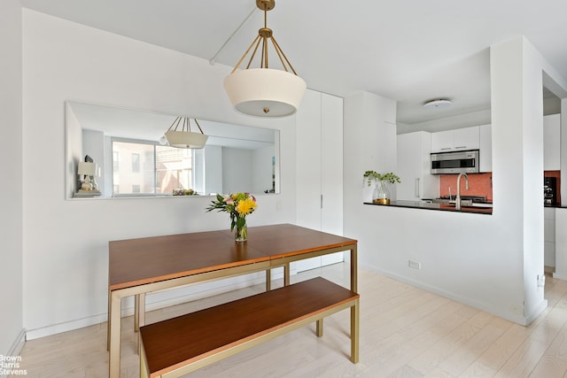 dining space featuring light wood-style flooring and baseboards