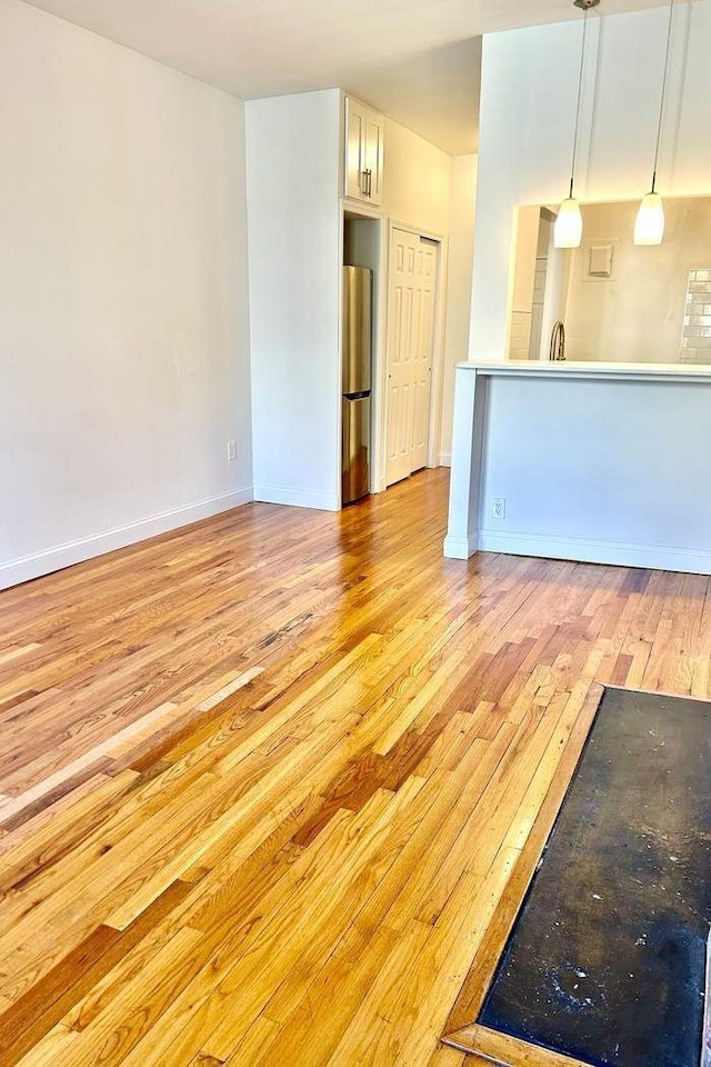 unfurnished living room featuring light wood finished floors and baseboards