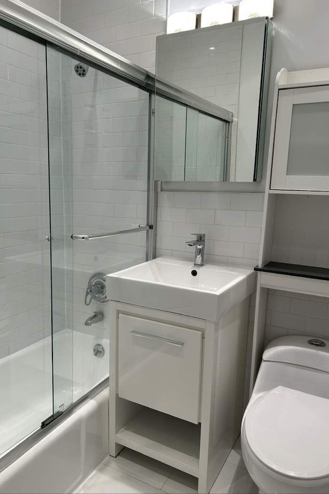 bathroom featuring toilet, backsplash, tile walls, enclosed tub / shower combo, and vanity