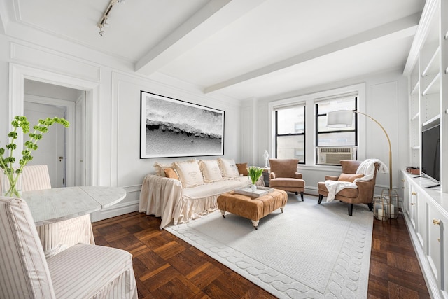 living room featuring a decorative wall, beamed ceiling, and rail lighting