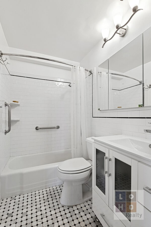 full bath featuring vanity, shower / bath combo with shower curtain, tile walls, toilet, and tasteful backsplash