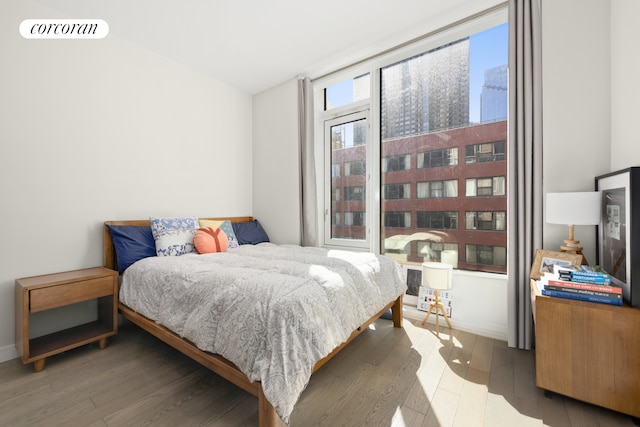 bedroom with visible vents, a city view, and wood finished floors